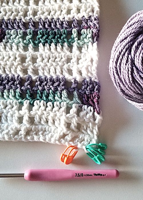 multiple stitch markers attached to corner of unfinished crochet project